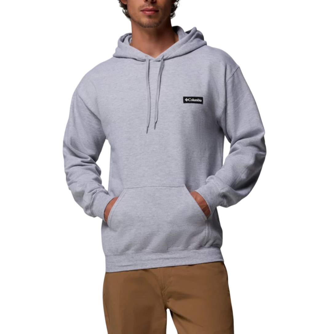 A man is wearing a light gray Columbia hoodie with a black chest logo, paired with brown pants.