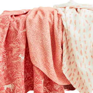 Three textiles in coral and white shades feature different patterns: a jungle scene, small dots, and abstract brush strokes.