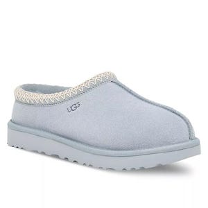 Light blue UGG Tasman slippers featuring a cozy, slip-on design with a suede exterior, decorative stitching near the opening, and a robust, textured sole for indoor and outdoor wear.