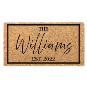 A coir doormat with a black border features the text \“The Williams\“ in a cursive script and \“Est. 2022\“ in a bold font.