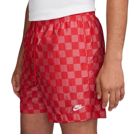 Red and pink checkered Nike shorts with an elastic waistband and drawstring. The Nike logo is embroidered in white on the lower hem.