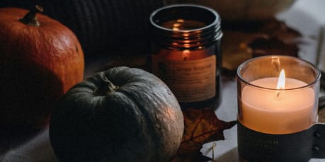 a table topped with a candle next to a pile of pumpkins