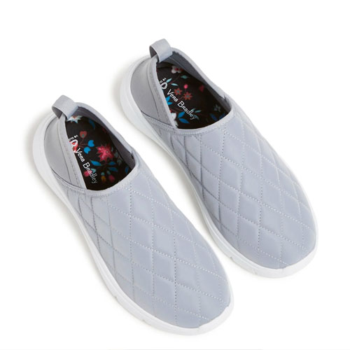 A pair of light gray, quilted slip-on sneakers with floral insoles.