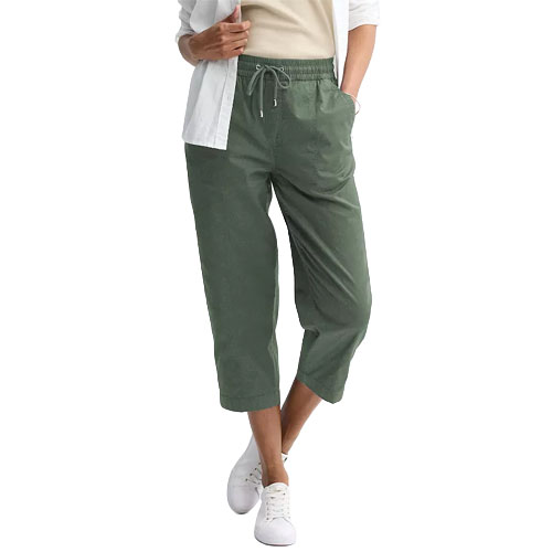A person wears cropped green drawstring pants paired with a white shirt and sneakers.