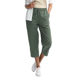 A person wears cropped green drawstring pants paired with a white shirt and sneakers.