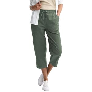 A person wears cropped green drawstring pants paired with a white shirt and sneakers.