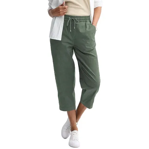A person wears cropped green drawstring pants paired with a white shirt and sneakers.