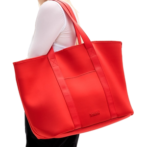 The Athleta Wipe-Clean XL Tote is a large, bright red bag with sturdy, stitched handles and a front pocket, designed for easy cleaning and ample storage.