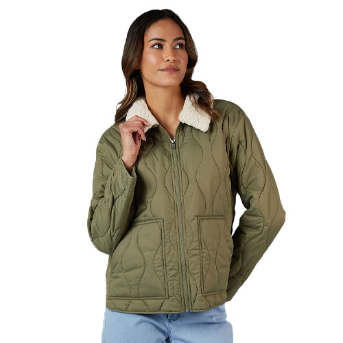 A woman is wearing a quilted olive green jacket with a white fleece collar, paired with light blue jeans.