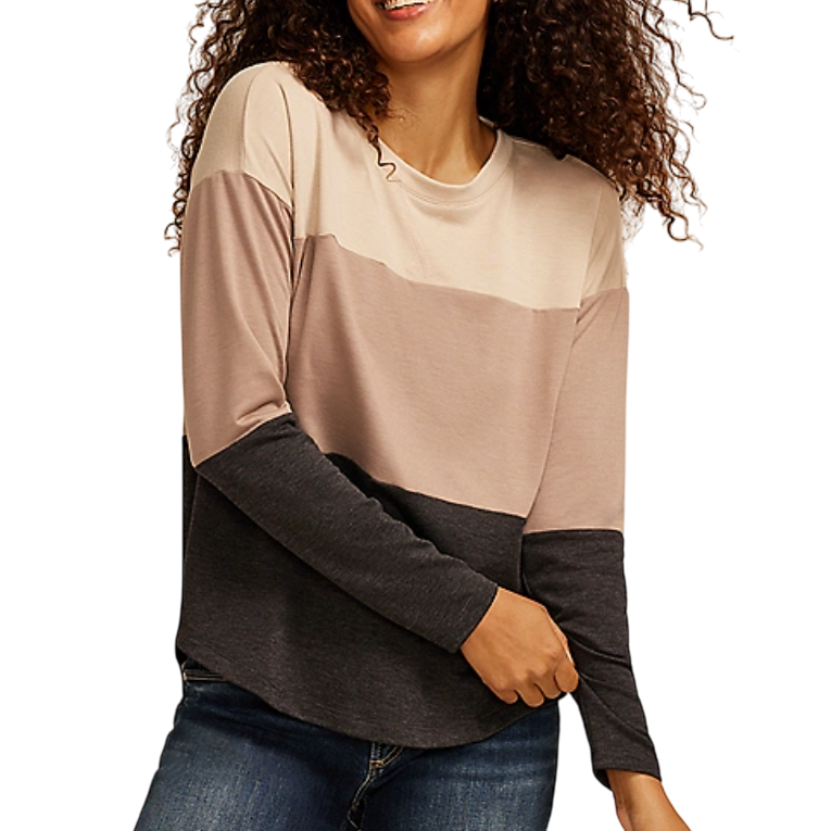 A woman wears a long-sleeve color-blocked shirt with beige, light brown, and dark gray horizontal stripes, paired with blue jeans.