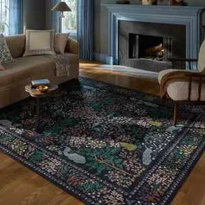 Living room with a beige sofa, blue-framed fireplace, blue curtains, patterned rug with nature motifs, wooden side table, and a cushioned armchair. Decor includes a lamp and wall sconces.