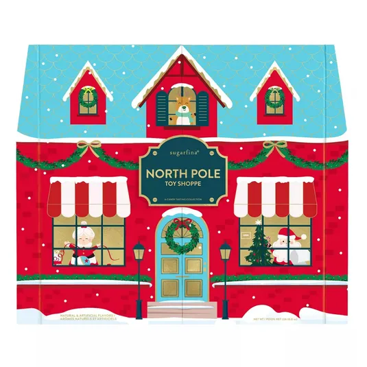 Sugarfina North Pole Toy Shoppe box features Christmas-themed artwork with snow, Santa, and holiday decorations. It is a candy tasting collection with festive design elements like wreaths and garlands.