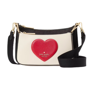 Kate Spade leather crossbody bag features a white body with a prominent red heart and gold-tone hardware, complemented by a detachable black strap. The brand's logo is embossed below the heart design.