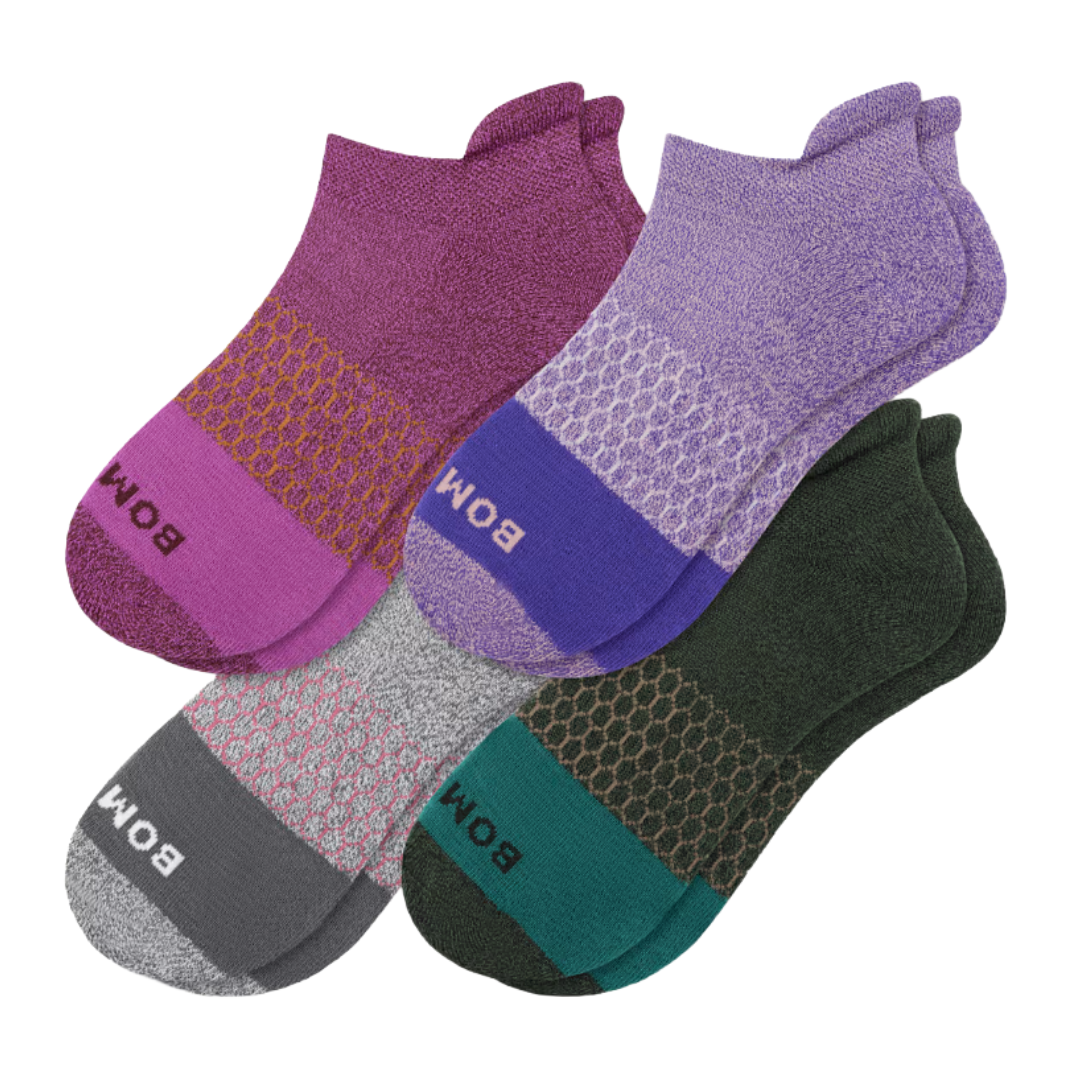A set of colorful ankle socks featuring patterns and contrasting heel and toe sections in shades of purple, pink, gray, and green, each with the brand name \“BOMB\“ on the toes.