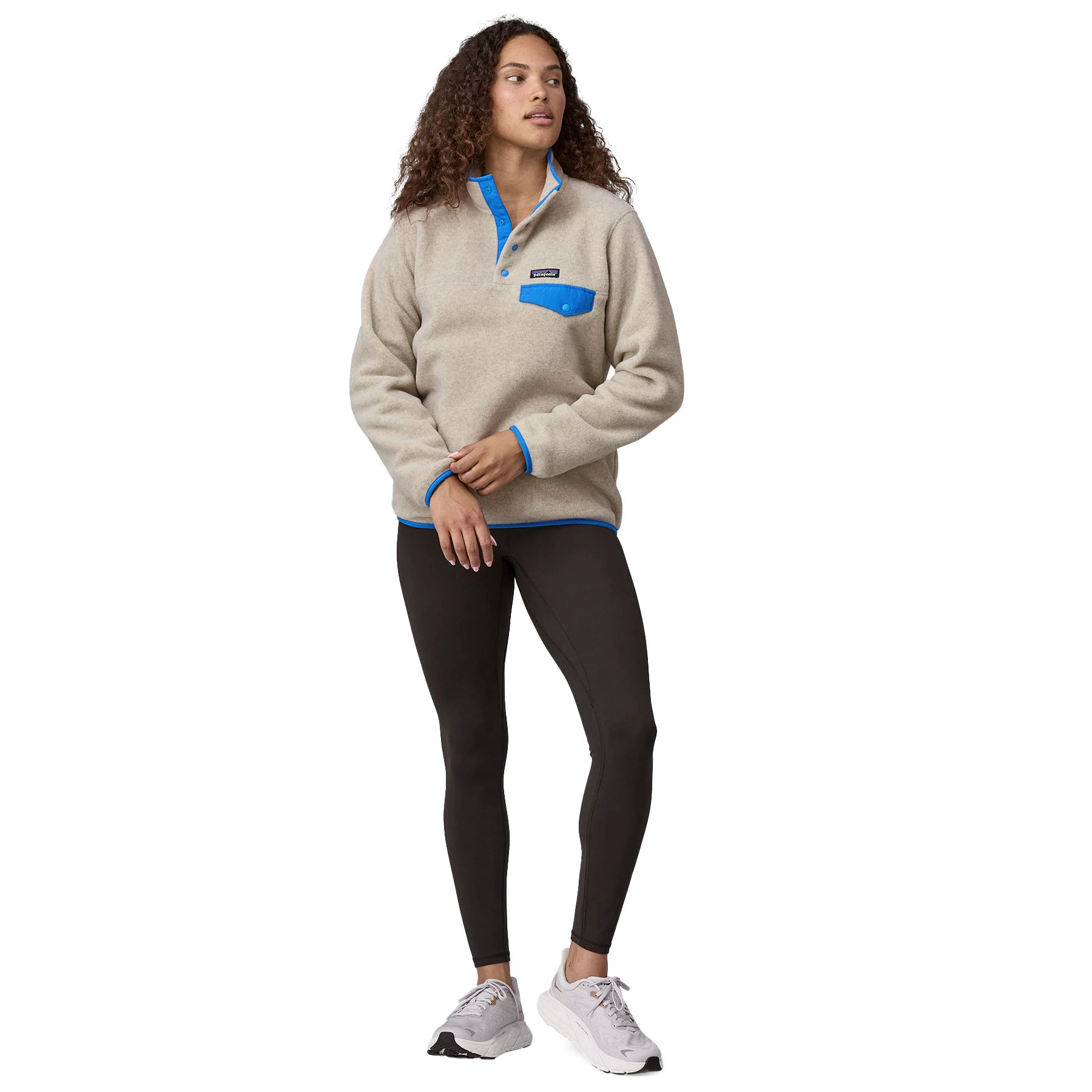 Cream-colored Patagonia Synchilla fleece with blue accents, snap-button collar, and a contrasting blue chest pocket, paired with black leggings and white sneakers.