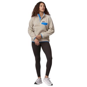 Cream-colored Patagonia Synchilla fleece with blue accents, snap-button collar, and a contrasting blue chest pocket, paired with black leggings and white sneakers.