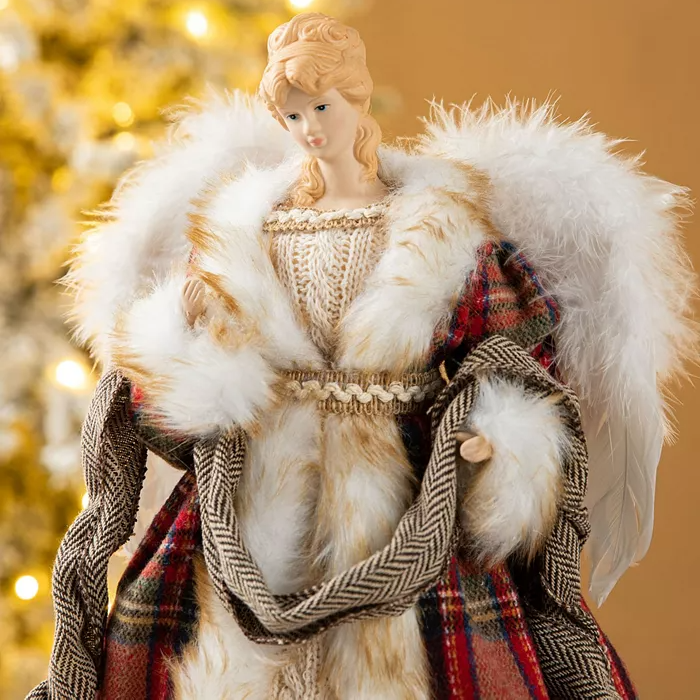 A blonde angel tree topper with curly hair, wearing a red and green plaid robe trimmed with gold thread and faux fur. It features white feathered wings and holds a herringbone sash.