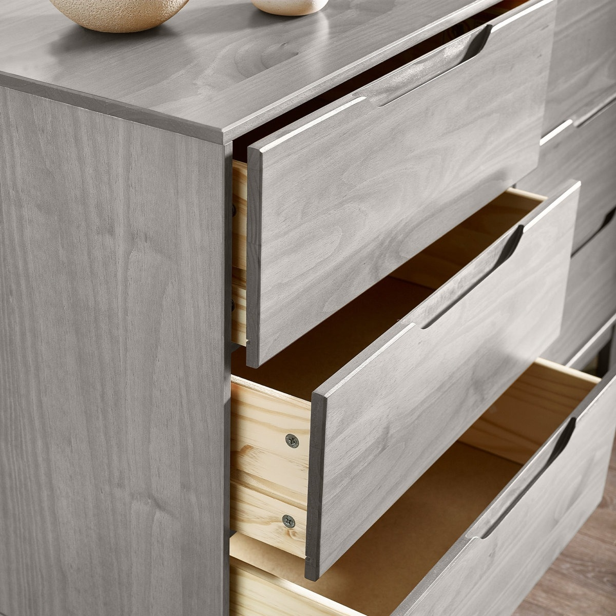 A gray wooden dresser with several open drawers, showcasing a sleek design and simple pull handles.