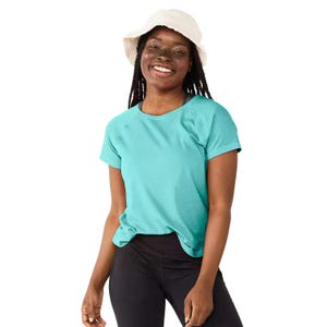 Woman wearing a turquoise T-shirt, black leggings, and a white bucket hat, smiling.