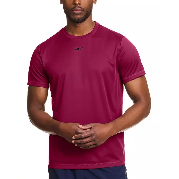 A man is wearing a burgundy Reebok athletic T-shirt with a small logo on the chest, paired with dark shorts.