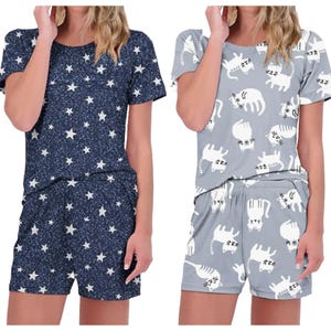 Two sets of women's short-sleeve pajama tops and shorts: one in navy with white stars, and the other in gray with white cat illustrations.