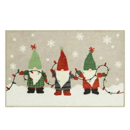 A decorative doormat featuring three gnomes holding colorful string lights, set against a snowy background with falling snowflakes.