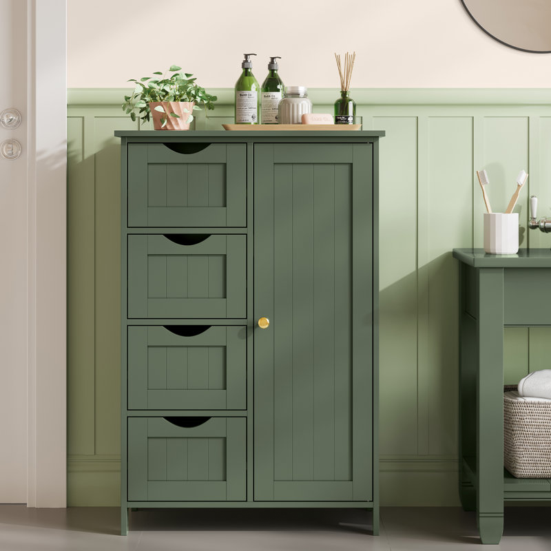 Green bathroom cabinet with three drawers and a door, featuring a potted plant, liquid bottles, and a reed diffuser on top.