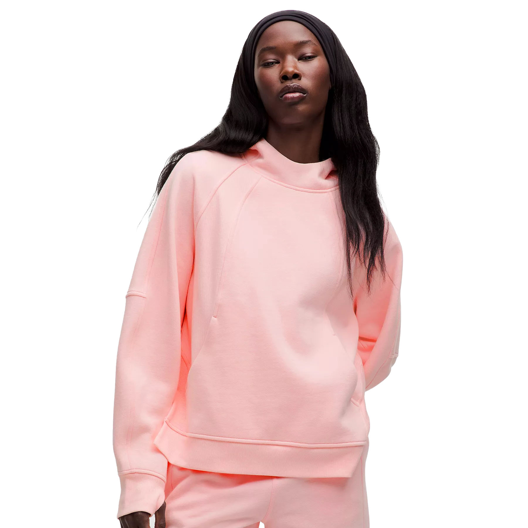 A model is wearing a pastel pink oversized hoodie with a loose fit, featuring long sleeves, a relaxed neckline, and a soft, comfortable fabric.