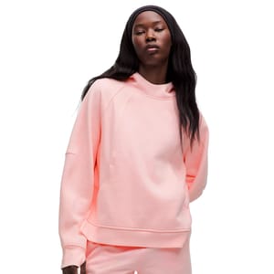 A model is wearing a pastel pink oversized hoodie with a loose fit, featuring long sleeves, a relaxed neckline, and a soft, comfortable fabric.