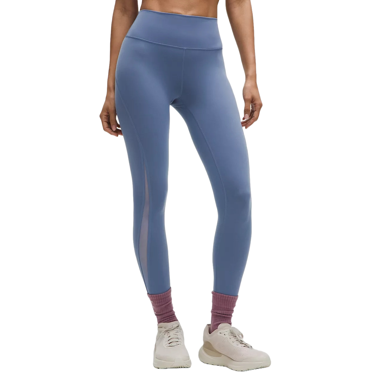 A person wears high-waisted blue leggings with mesh panels, paired with light pink socks and cream-colored sneakers.