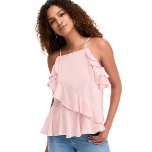 A woman wearing a light pink, sleeveless blouse with ruffled details, paired with blue jeans.