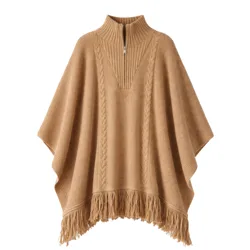 A camel-colored poncho featuring a cable knit design, high collar with a partial zip, and fringed hem.