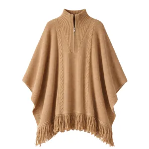 A camel-colored poncho featuring a cable knit design, high collar with a partial zip, and fringed hem.