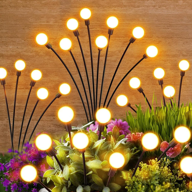 A cluster of outdoor garden lights on flexible stems, glowing yellow, is displayed among greenery and flowers.