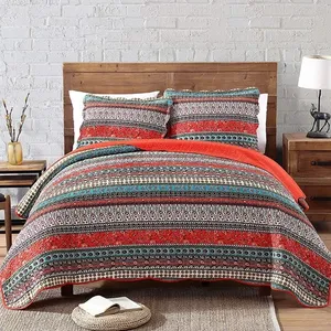 A patterned bedding set with red and turquoise colors, including a comforter and two pillowcases on a wooden bed frame.