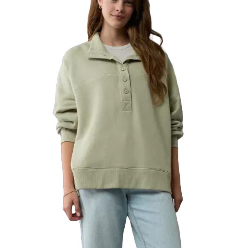 A woman is wearing a light green Henley sweater from American Eagle, featuring a buttoned neckline, long sleeves, and a relaxed fit. It is paired with light blue jeans.