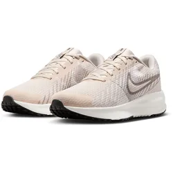 Beige and white Nike running shoes with a mesh upper, subtle swoosh design, and black soles.
