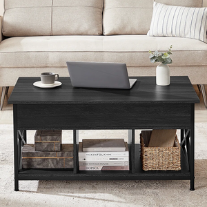 A living room scene features a beige sofa with a black wooden coffee table in front. The table holds a laptop, mug, and vase, and has shelves with books and a wicker basket underneath.