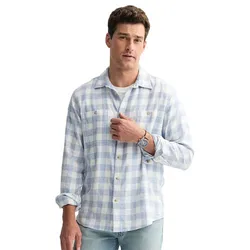 A man wearing a light blue plaid button-up shirt with long sleeves and light blue jeans.