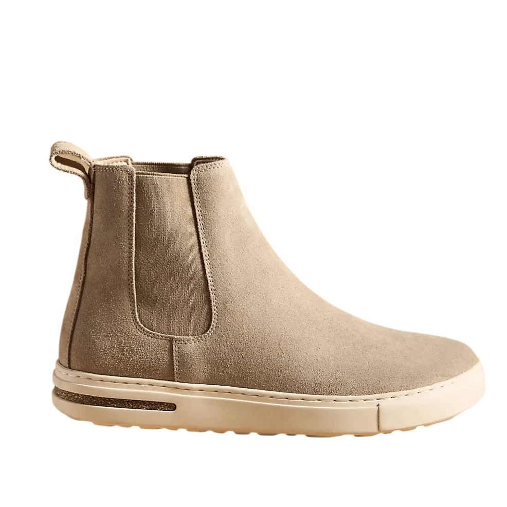Taupe suede Chelsea boot with a white rubber sole, elastic side panels, and a pull tab at the back for easy wearing.