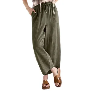 Woman wearing olive green, wide-leg pants with a drawstring waistband, paired with a striped top and brown platform sandals.