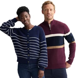 Two people are wearing sweaters: the woman in a navy blue cardigan with white stripes and the man in a burgundy quarter-zip sweater with navy, white, and tan stripes.