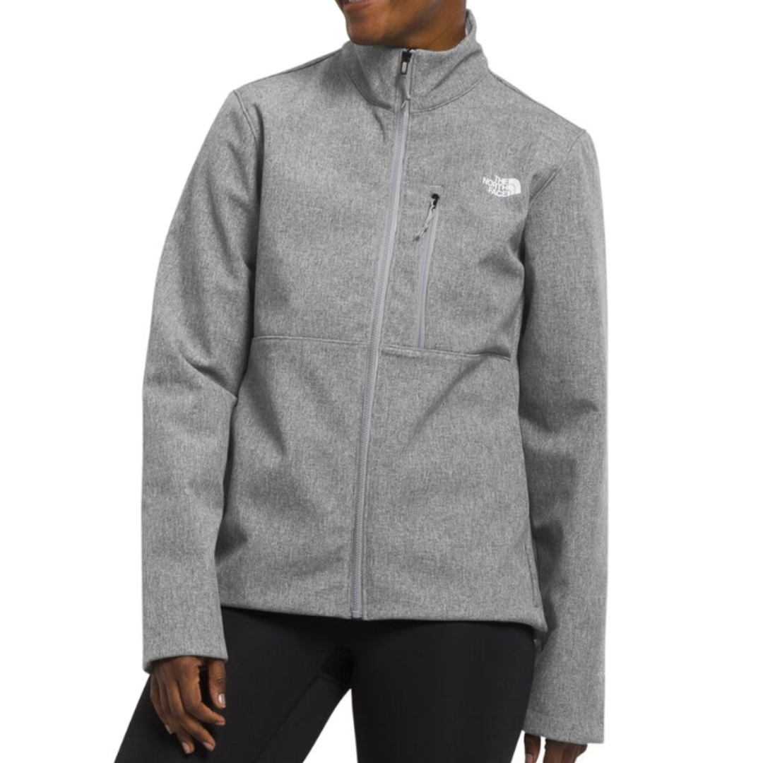 Gray high-neck jacket with front zipper, chest pocket, and The North Face logo on the chest, worn over black leggings.