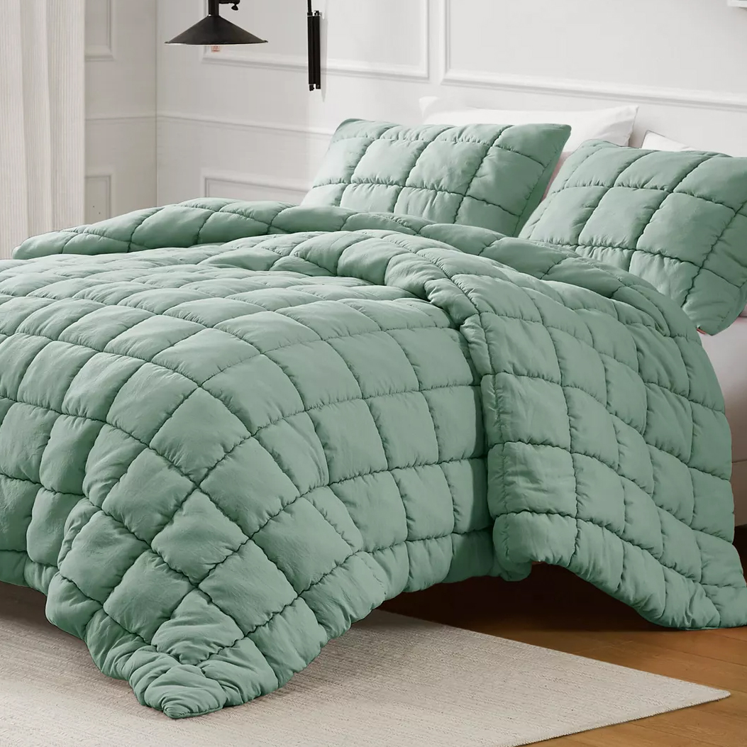 A light green quilted comforter set with a grid pattern, featuring matching pillow shams on a neatly made bed in a modern bedroom setting.