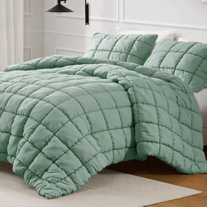 A light green quilted comforter set with a grid pattern, featuring matching pillow shams on a neatly made bed in a modern bedroom setting.
