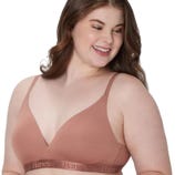 A woman is wearing a Hanes branded bra in a nude color, featuring a seamless, wire-free design with adjustable straps.
