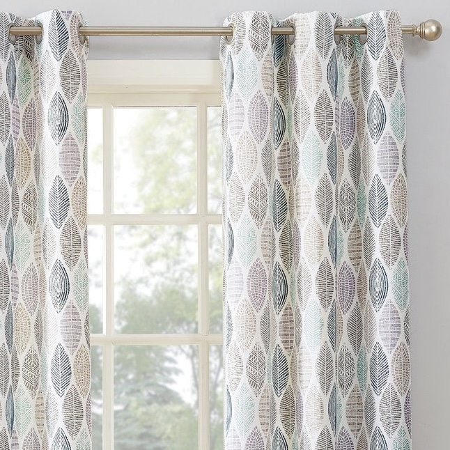 Curtains with a leaf pattern in shades of gray, blue, and green hang on a silver rod in front of a window.