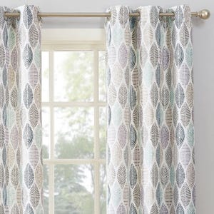 Curtains with a leaf pattern in shades of gray, blue, and green hang on a silver rod in front of a window.