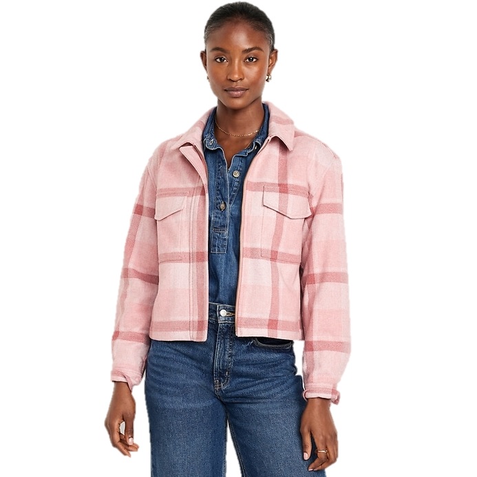 A woman is wearing a pink and white plaid relaxed shirt jacket with front pockets over a denim outfit.