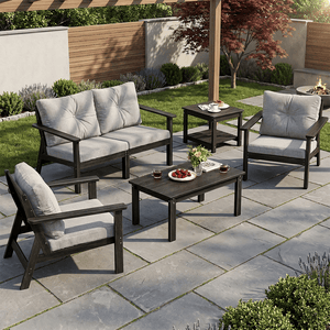 Outdoor patio set with two cushioned chairs, a loveseat, a coffee table, and a side table on a stone patio. The set features dark wood frames and light gray cushions.